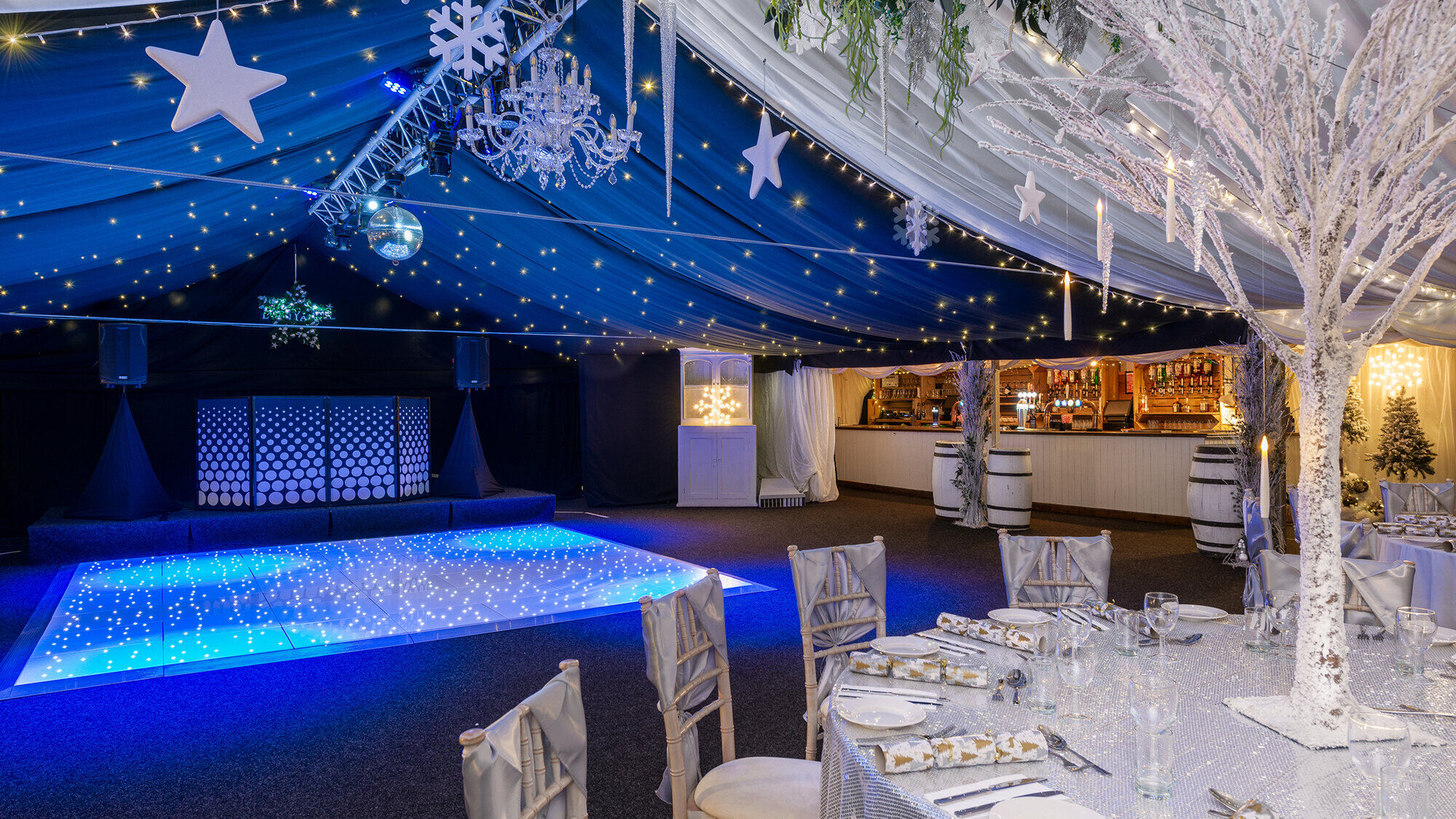 The Arboretum at Christmas, lit by chandeliers and fairy lights with stars and silver tables