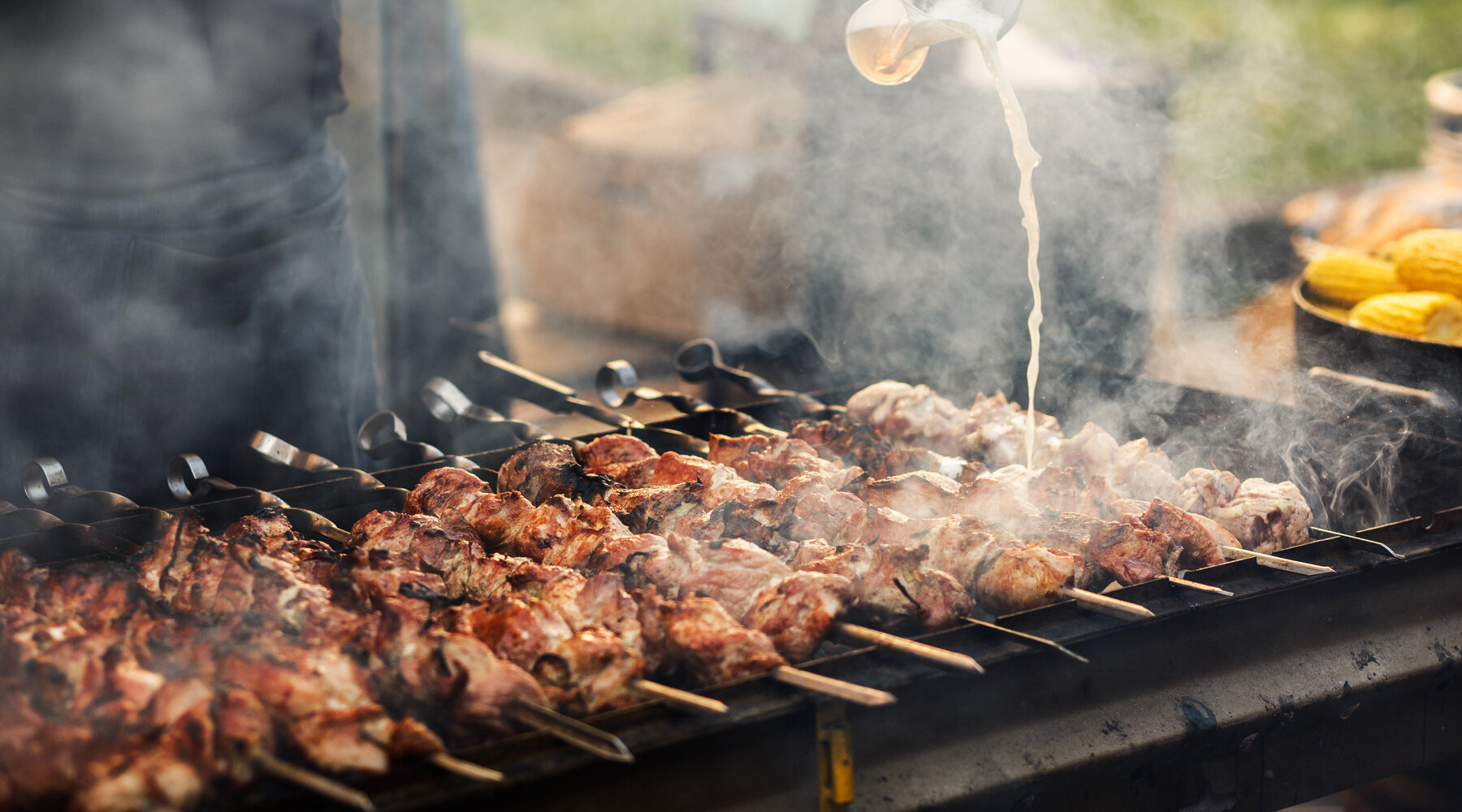 Skewers of marinated meat cooking over the coals on the BBQ at The BarnYard