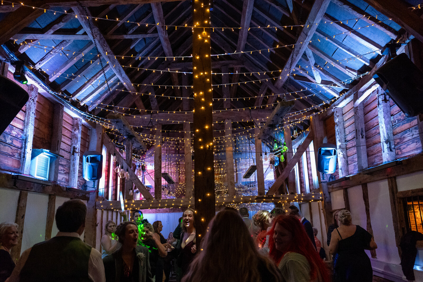 A packed dancefloor in the Apple Barn at The BarnYard, fairy lights strung between the beams