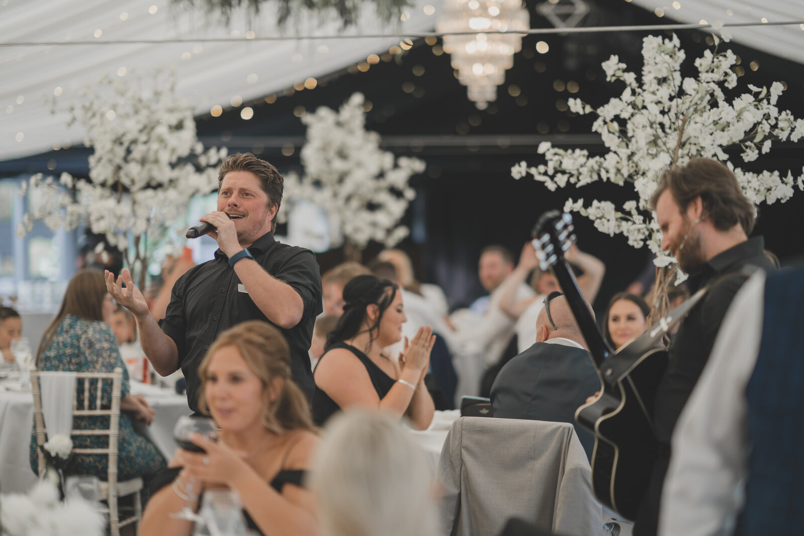 A singer performing between the tables at a dinner at The BarnYard, guests applauding