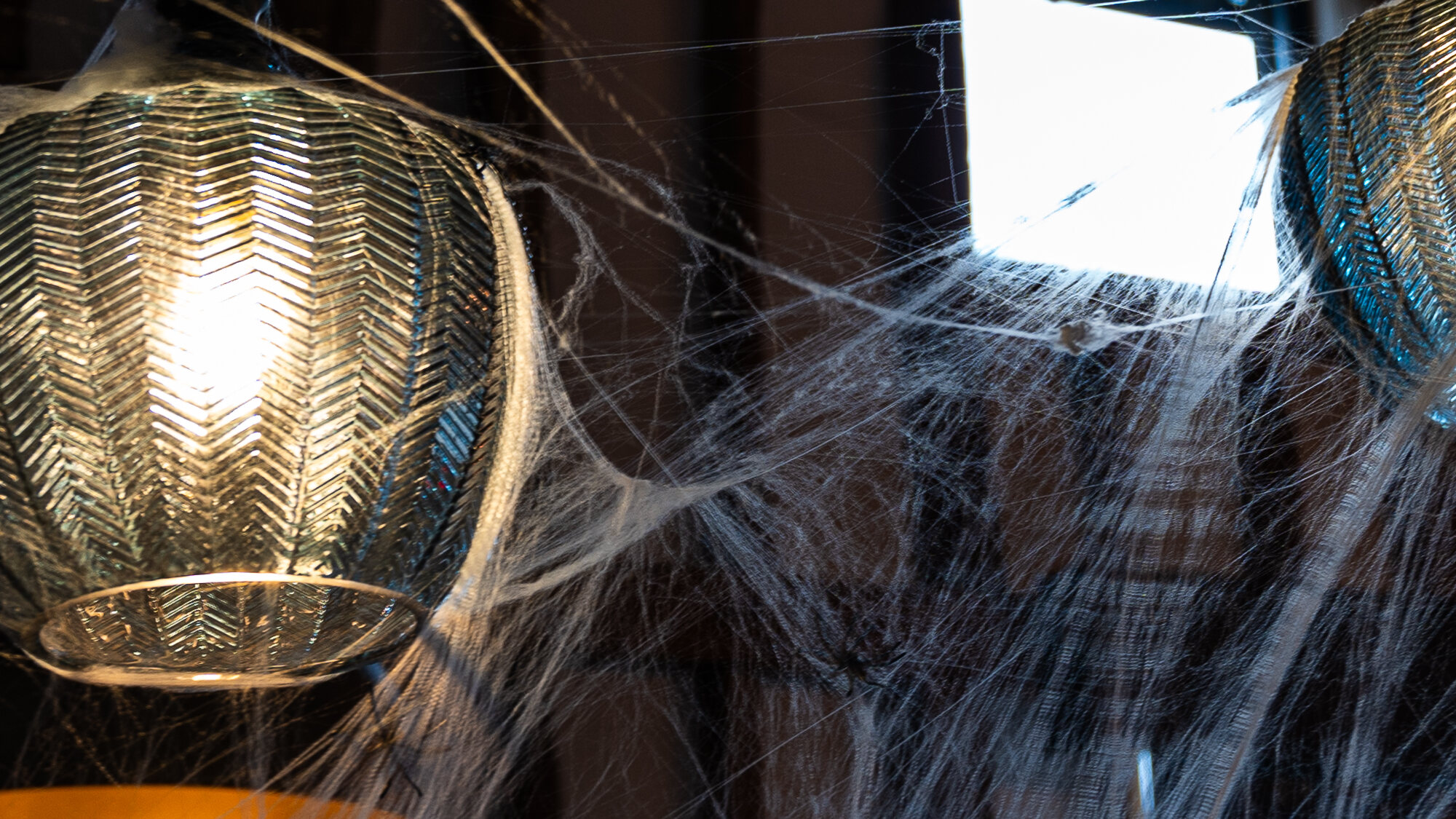 Cobwebs and spiders strung between the beams and lanterns at The Rooster, dressed for Halloween