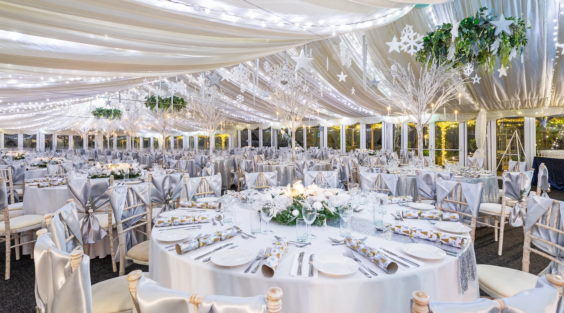 The Arboretum at The BarnYard dressed for a winter party, silver and white tables under a fairy-lit ceiling with the glazed doors running all the way round