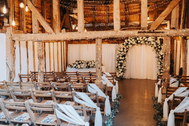 Wooden chairs dressed with ivory sashes, set for a ceremony in the Apple Barn