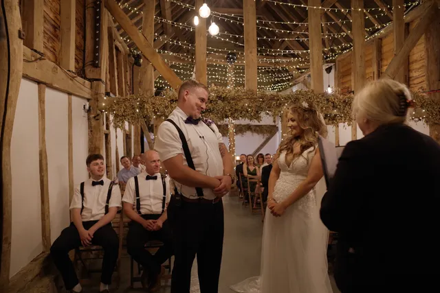 A groom waits at the altar as his bride arrives in the fairy-lit Apple Barn