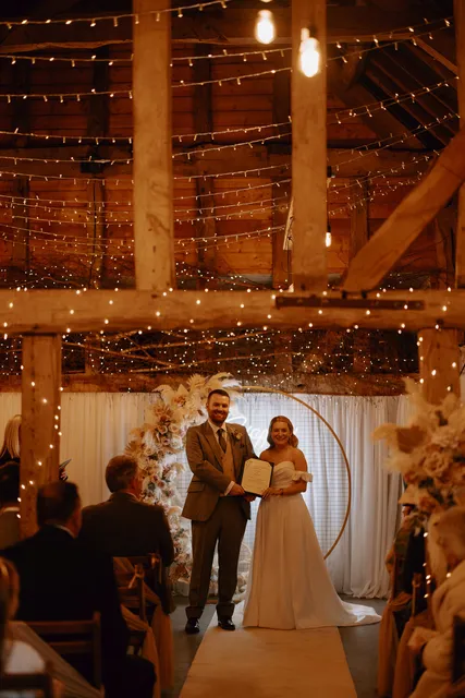 A couple sign the register beneath the fairy lights in the Apple Barn