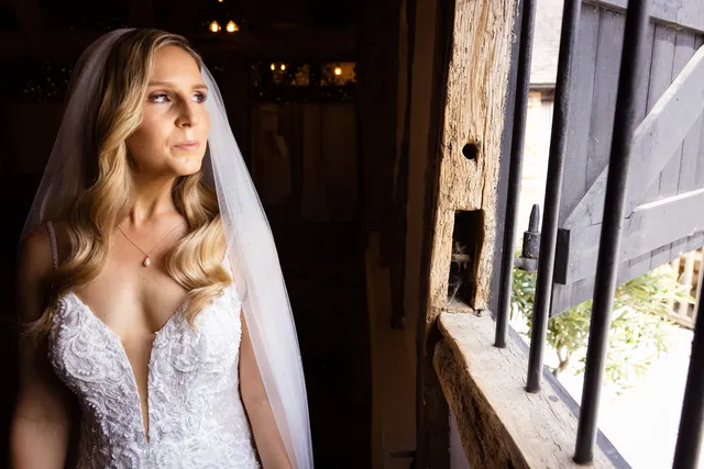 A bride in her veil beside the Apple Barn's timber frame