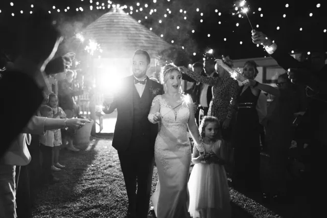 A couple walk through their guests, in black and white