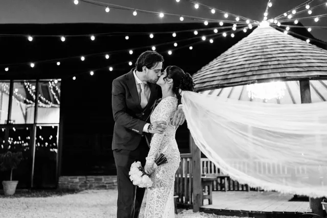 A couple kiss beneath the festoon lights outside the Apple Barn