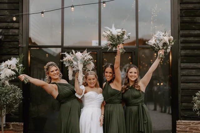 Bridesmaids in green celebrating at the Apple Barn windows