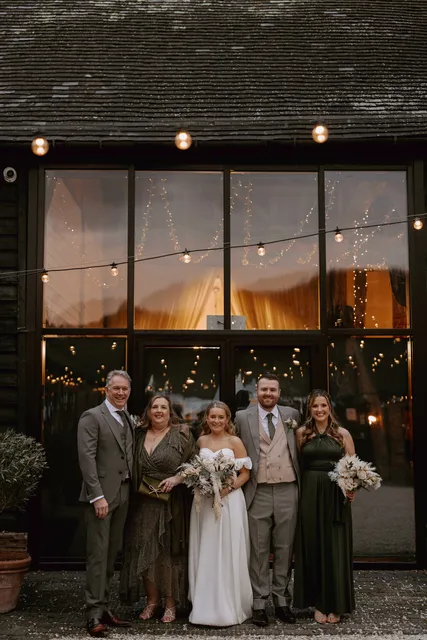 A wedding party outside the lit Apple Barn at dusk