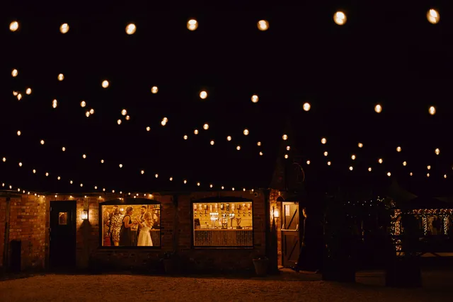 Festoon lights above the Courtyard with the Apple Barn glowing behind