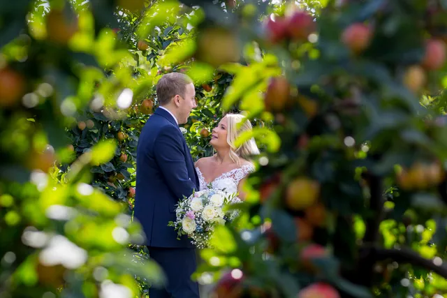 A couple among the apple trees in the orchard at The BarnYard
