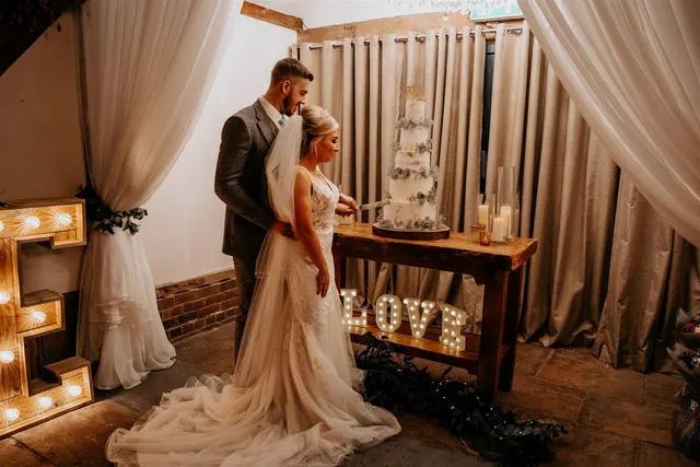 A couple beside light-up LOVE letters in the Apple Barn
