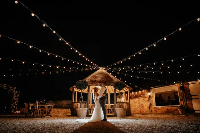 A bride alone in the lit Courtyard gazebo at night