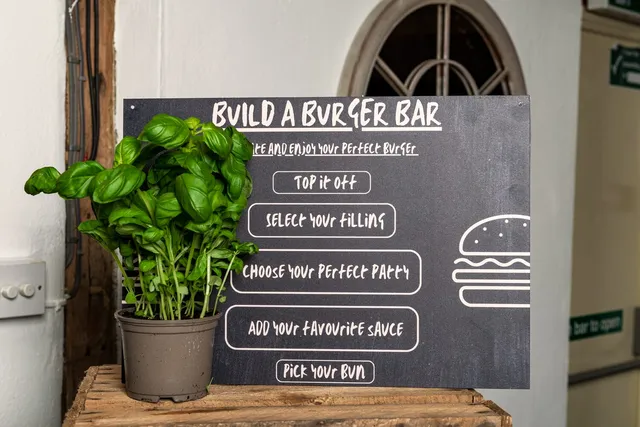 A Build a Burger Bar menu board beside a pot of fresh basil