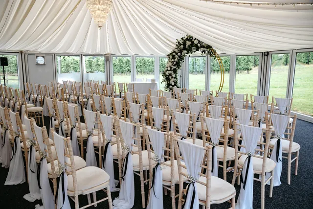 Chairs dressed in white with a floral moon gate at the front of the Arboretum