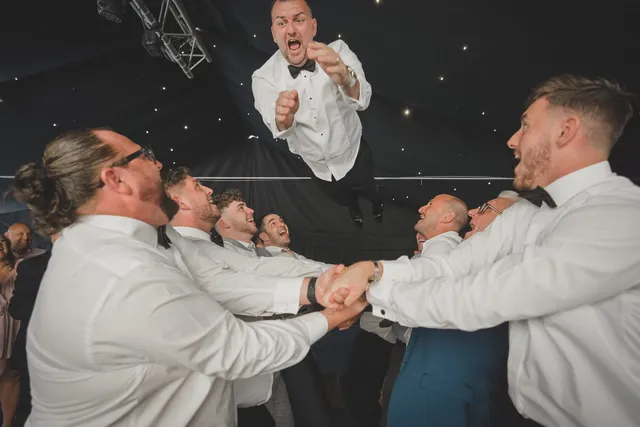 Guests lifting the groom on the dance floor