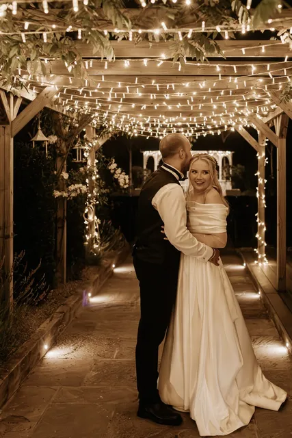 A couple dancing beneath the fairy lit pergola
