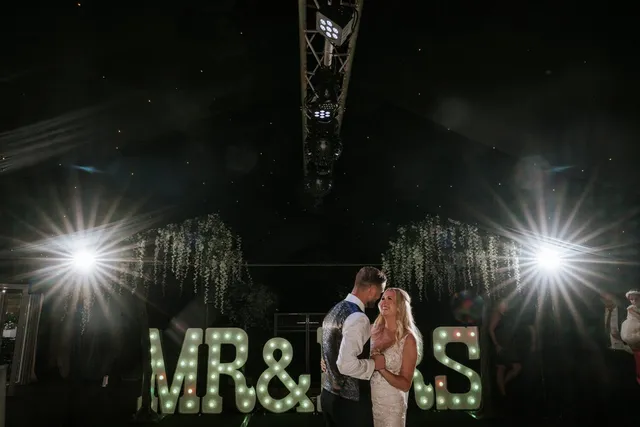 A couple beside illuminated Mr and Mrs letters