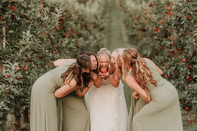 Bridesmaids laughing with the bride in the orchards