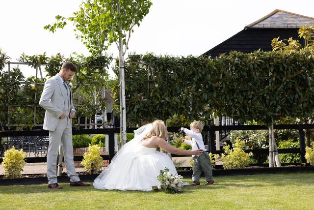A couple laughing with a pageboy on the lawn