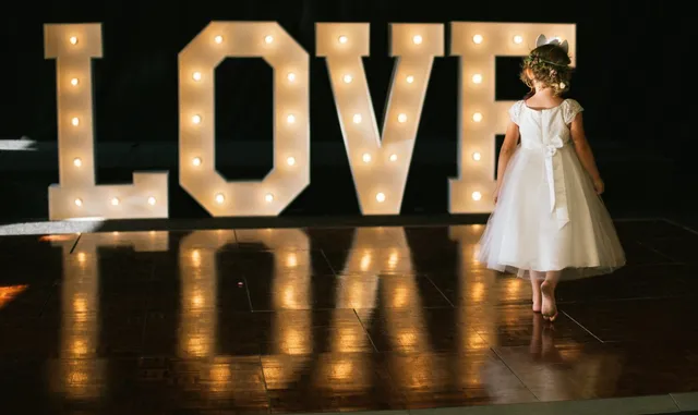 A flower girl in front of the illuminated LOVE letters