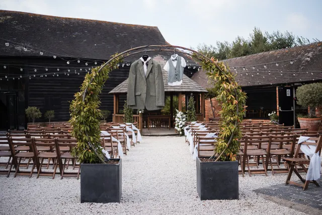 A greenery arch over the aisle for a Courtyard ceremony, chairs set either side