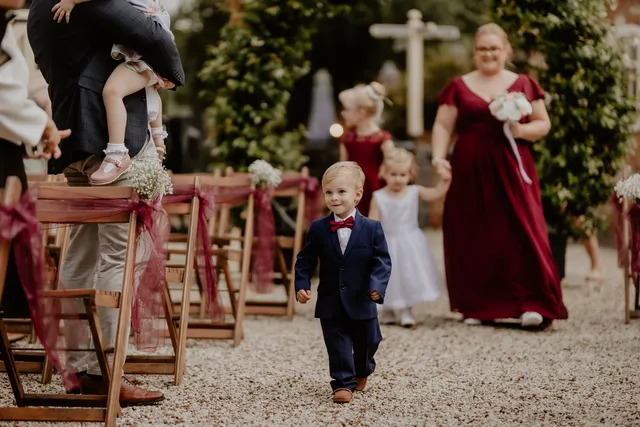 A page boy walks up the aisle at a Courtyard ceremony