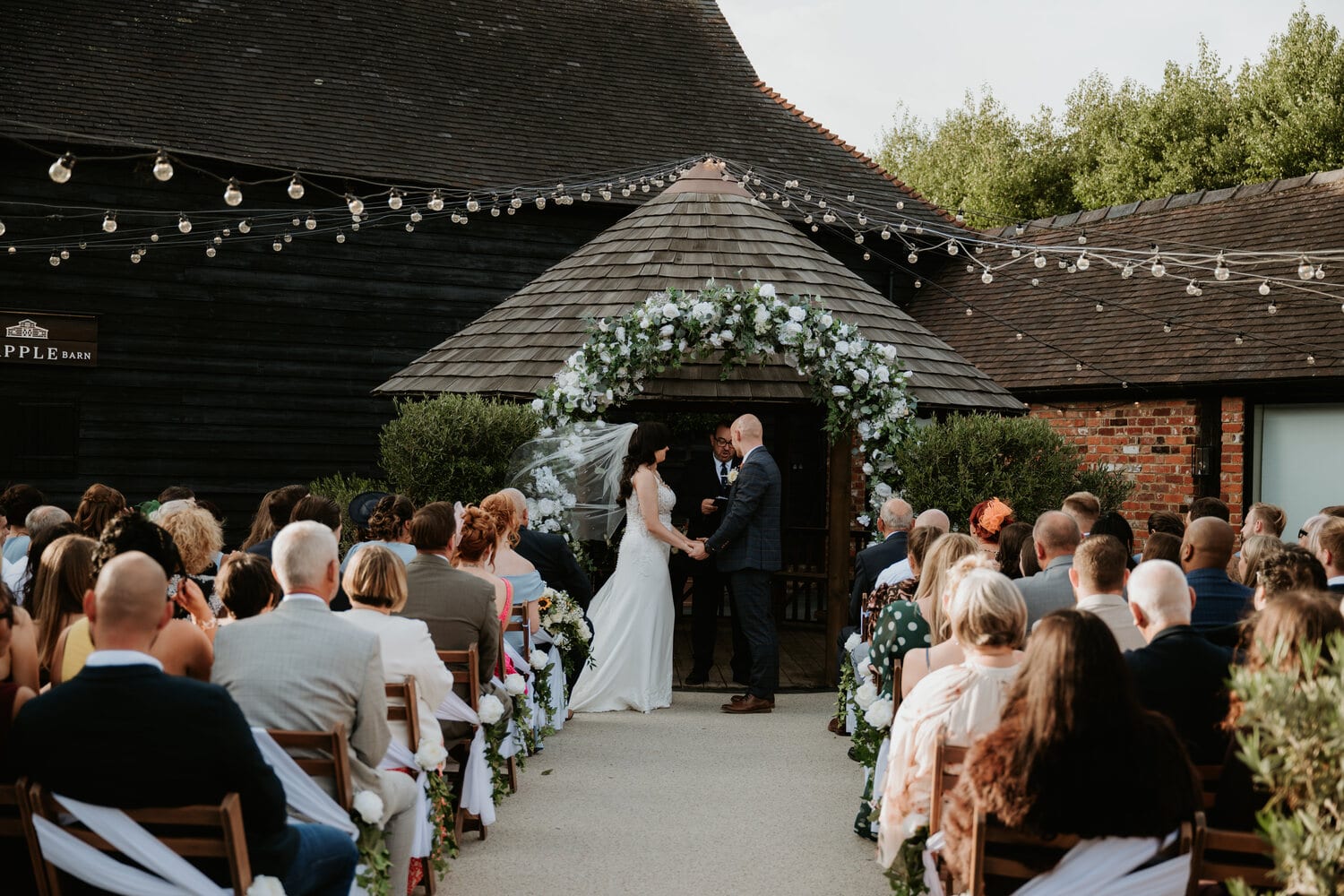 A couple at the courtyard gazebo with guests gathered