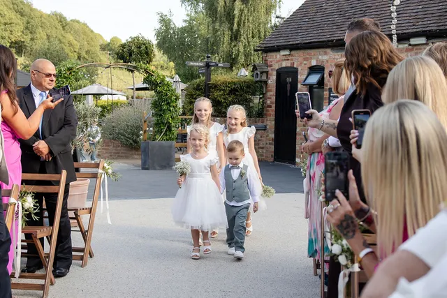 Flower girls and a page boy walk into a Courtyard ceremony