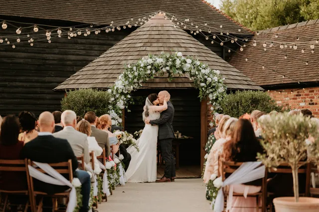 A couple kiss at the Courtyard gazebo surrounded by their guests