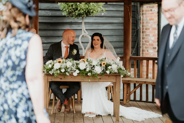 A couple sign the register at a table dressed with white florals