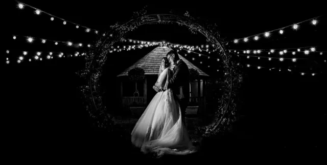 A couple under the fairy lit moon gate in the Courtyard at night