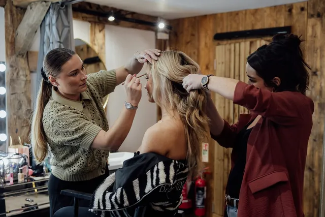 A bride having her hair finished in the dressing suite
