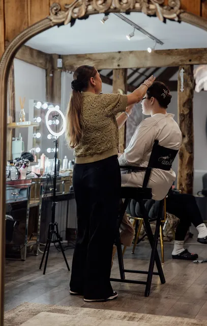 A hair stylist at work at the lit vanity mirrors