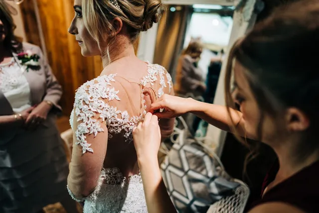 A bride's lace back being fastened button by button