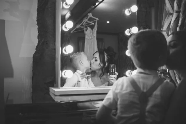 A pageboy kissing the bride in the vanity mirror
