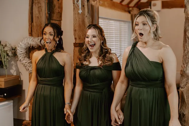 Bridesmaids in deep green dresses pulling faces together