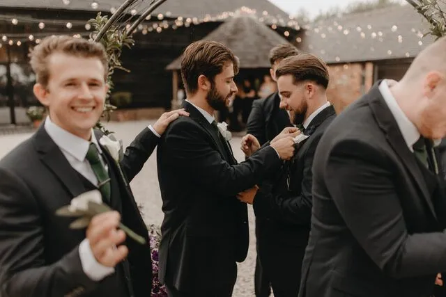 Groomsmen straightening each other's ties in the courtyard