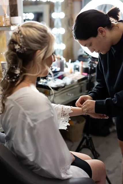 A bridesmaid's hair being pinned at the mirror