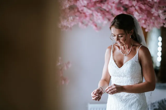 A bride under the blossom tree fastening her bracelet