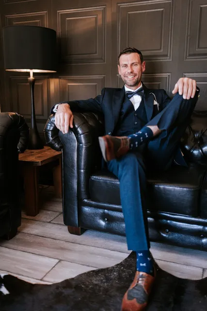 A groom relaxing on the leather sofa before the ceremony