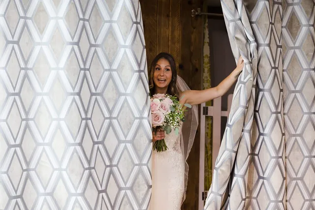 A bride stepping through the curtains with her bouquet