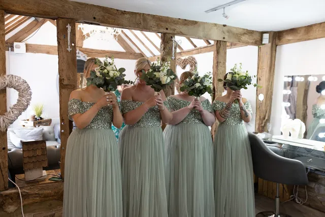 Bridesmaids in sage green holding their bouquets