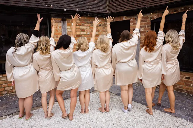 Bridesmaids in robes throwing their arms up together