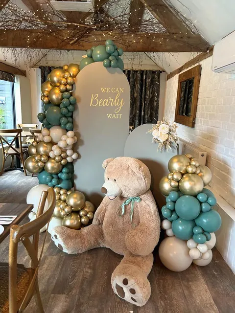 A teddy bear and balloon arch set up for a baby shower