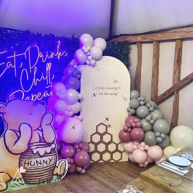 A Winnie the Pooh themed baby shower with a balloon arch and neon sign