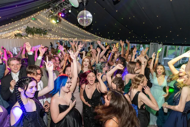 A packed prom dancefloor beneath a mirrorball