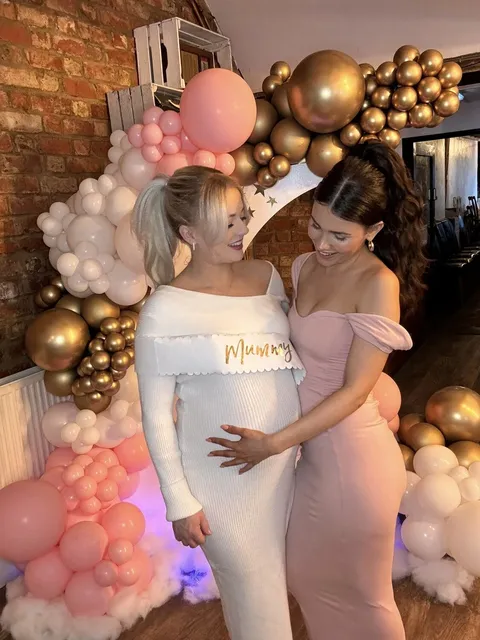 Friends together at a baby shower beside the balloon display