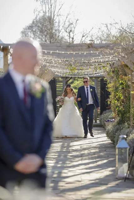 A bride walking the Lavender Walk aisle with her father